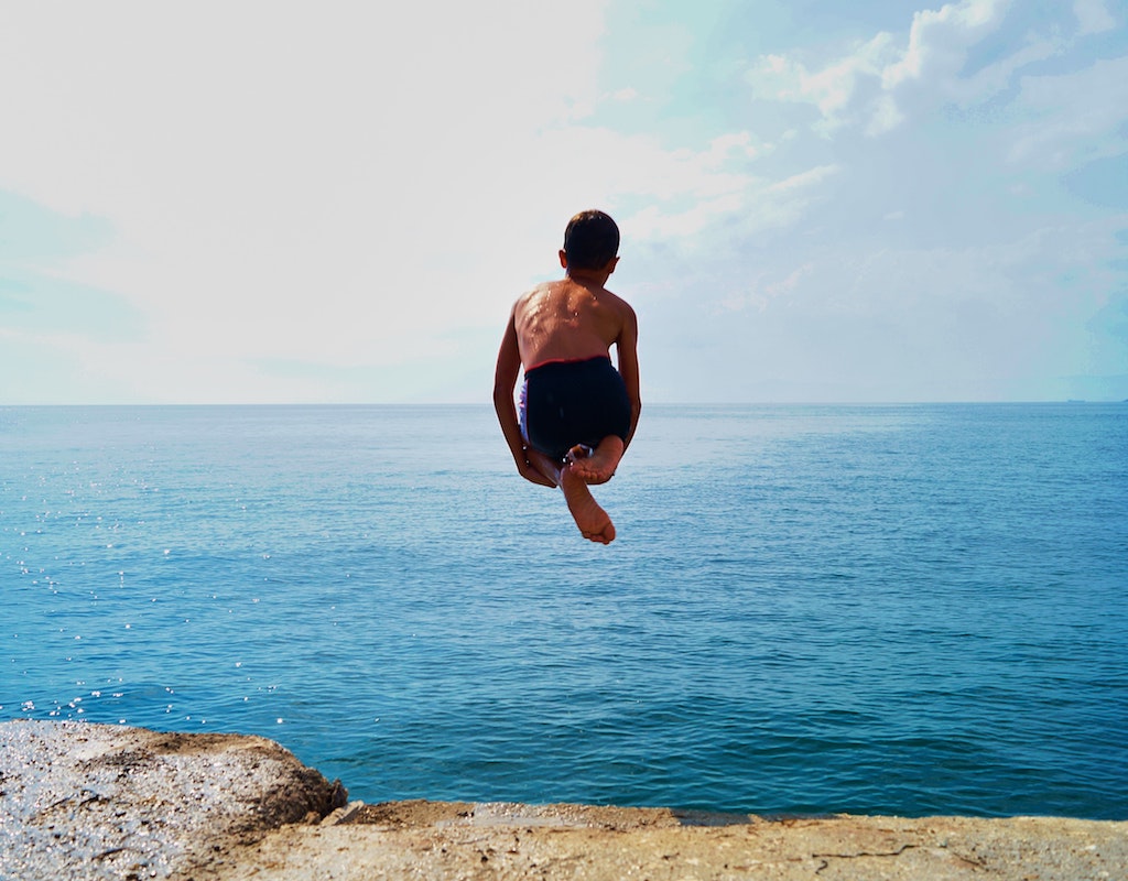 Young boy doing a cannonball into the ocean