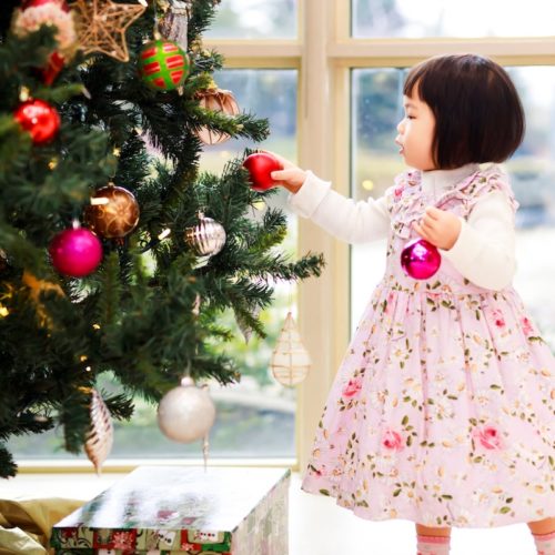 Little girl placing bulbs on a Christmas tree